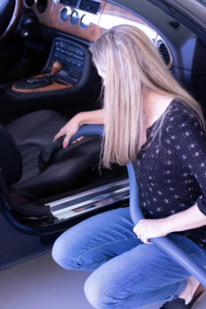 women using hide-a-hose to vacuum a car in a garage.